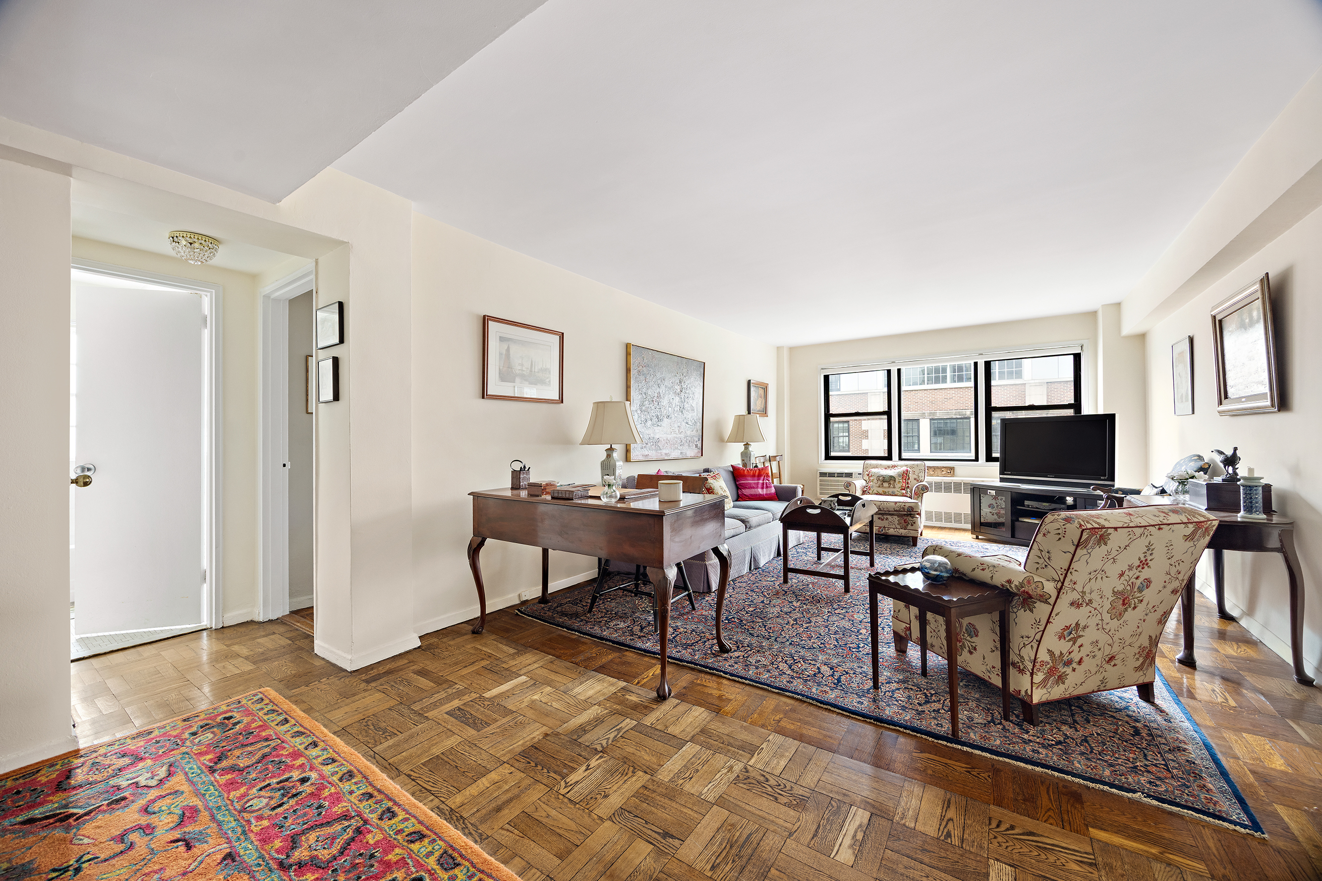 205 East 77th Street, Unit 11B Manhattan, NY 10075 - Photo 2 of 11 a living room with furniture and a flat screen tv