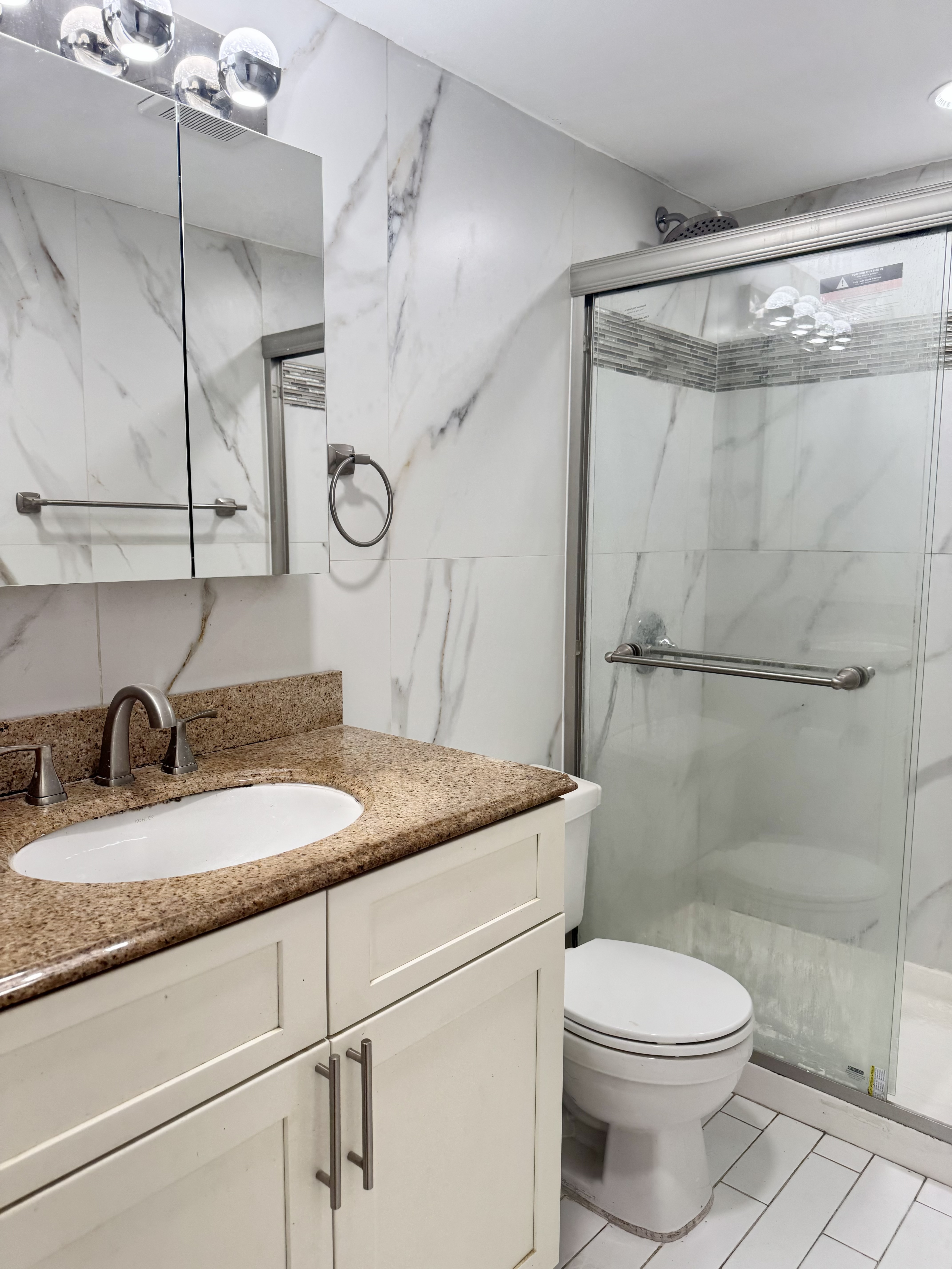 156-17 76th Street, Unit 1 Queens, NY 11414 - Photo 3 of 12 a bathroom with a granite countertop sink toilet and shower