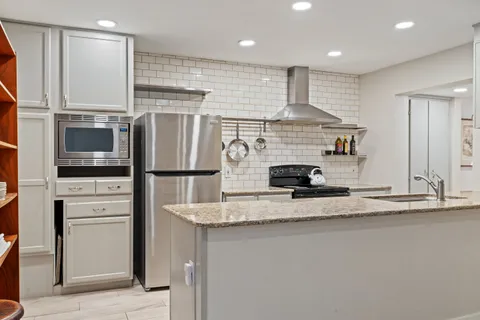 a kitchen with stainless steel appliances granite countertop a sink and a refrigerator