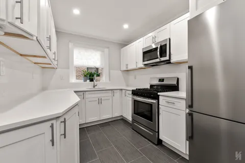 a kitchen with a sink a stove top oven and white stainless steel appliances