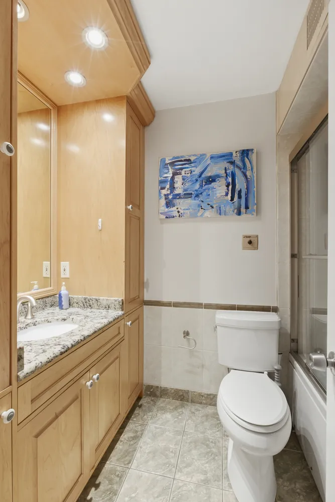 a bathroom with a granite countertop toilet sink and mirror