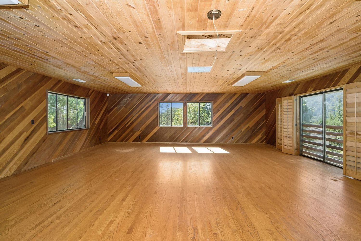 a view of an empty room with a window and wooden floor