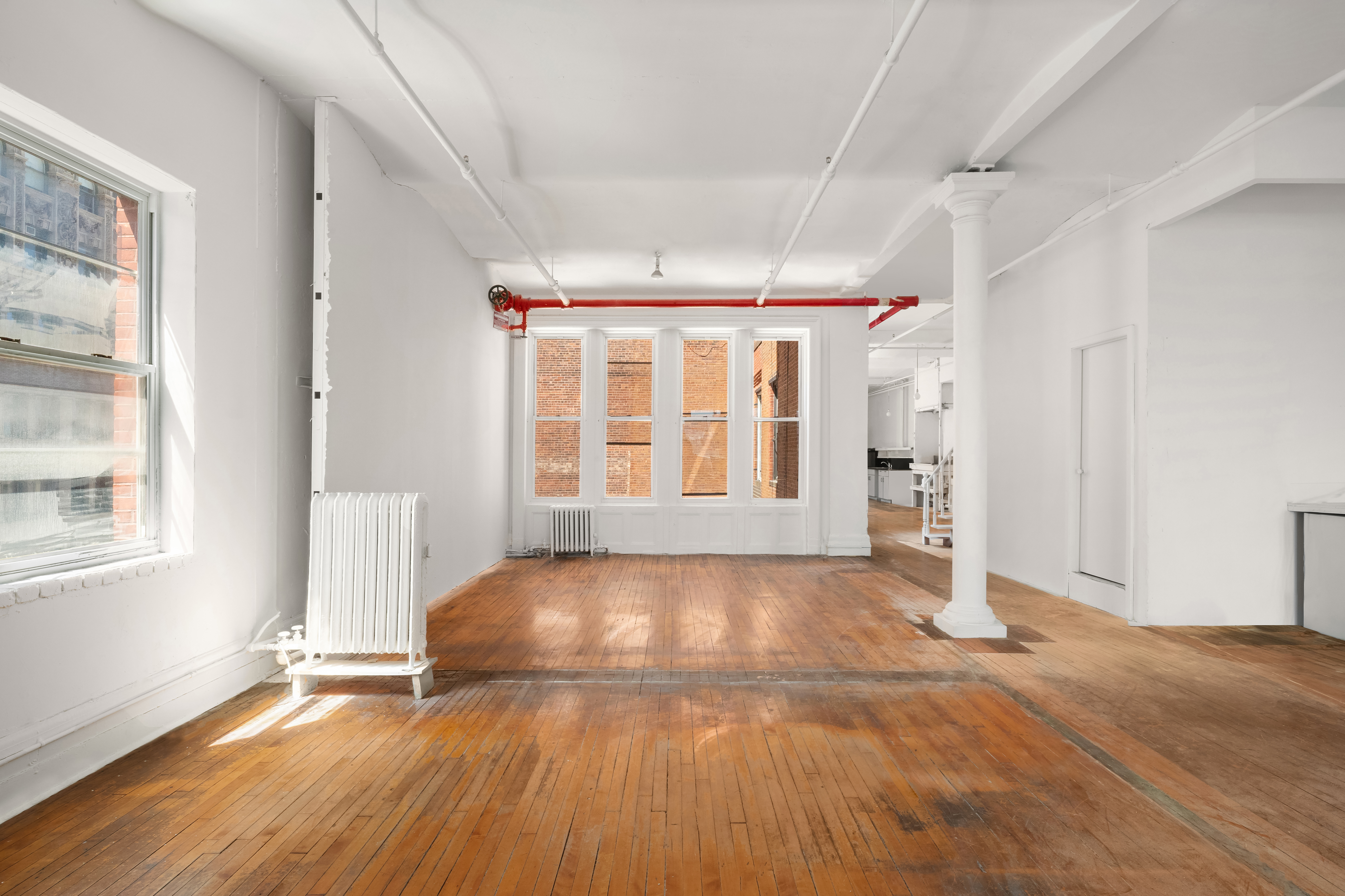 491 Broadway Manhattan, NY 10012 - Photo 6 of 11 an empty room with wooden floor and windows