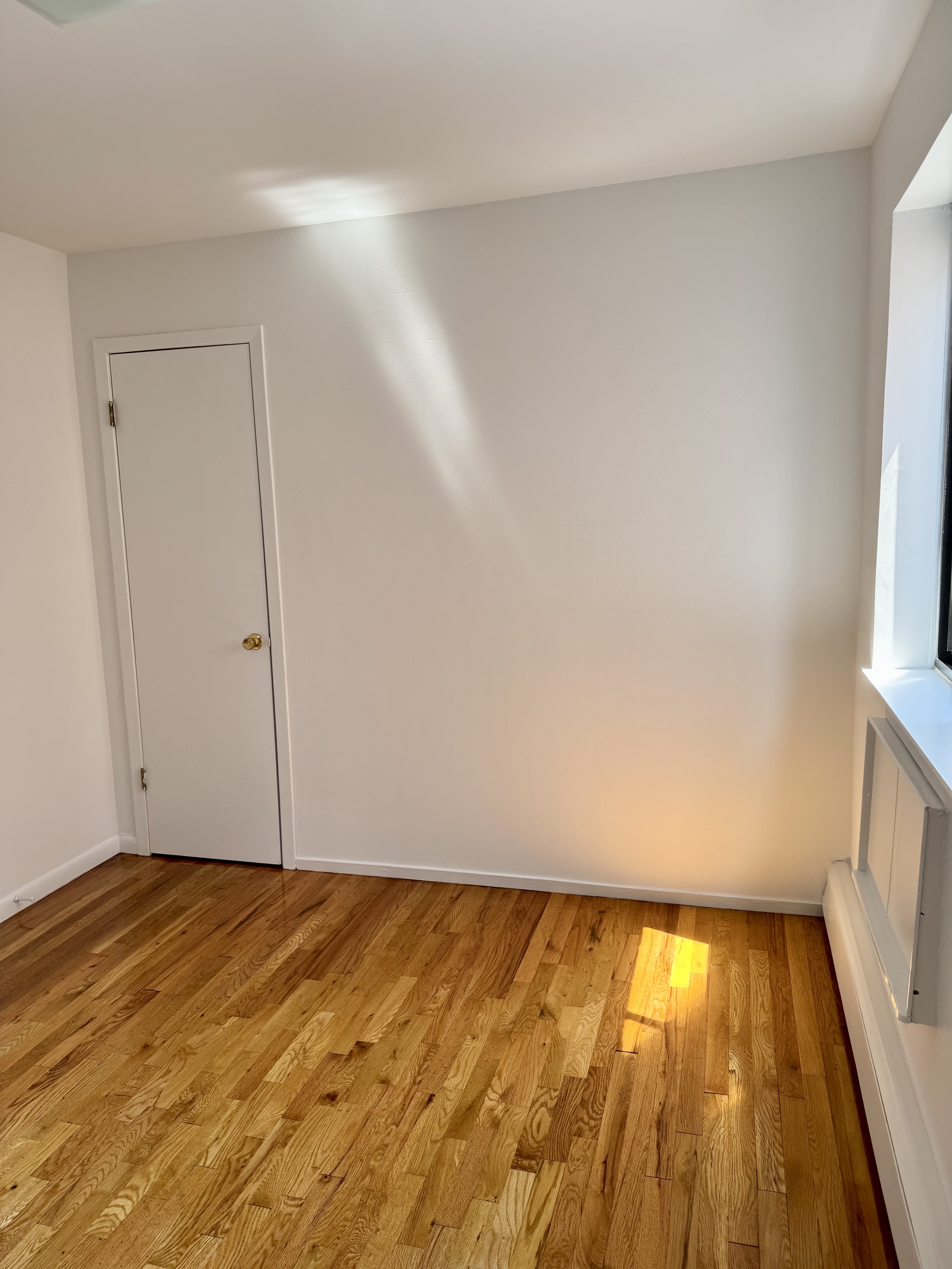 59-15 39th Avenue, Unit 2 Queens, NY 11377 - Photo 5 of 13 a view of an empty room with wooden floor and a window