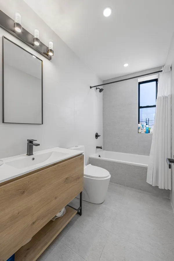 a spacious bathroom with a tub sink toilet and mirror