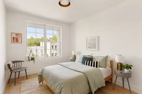 a spacious bedroom with a bed and wooden floor