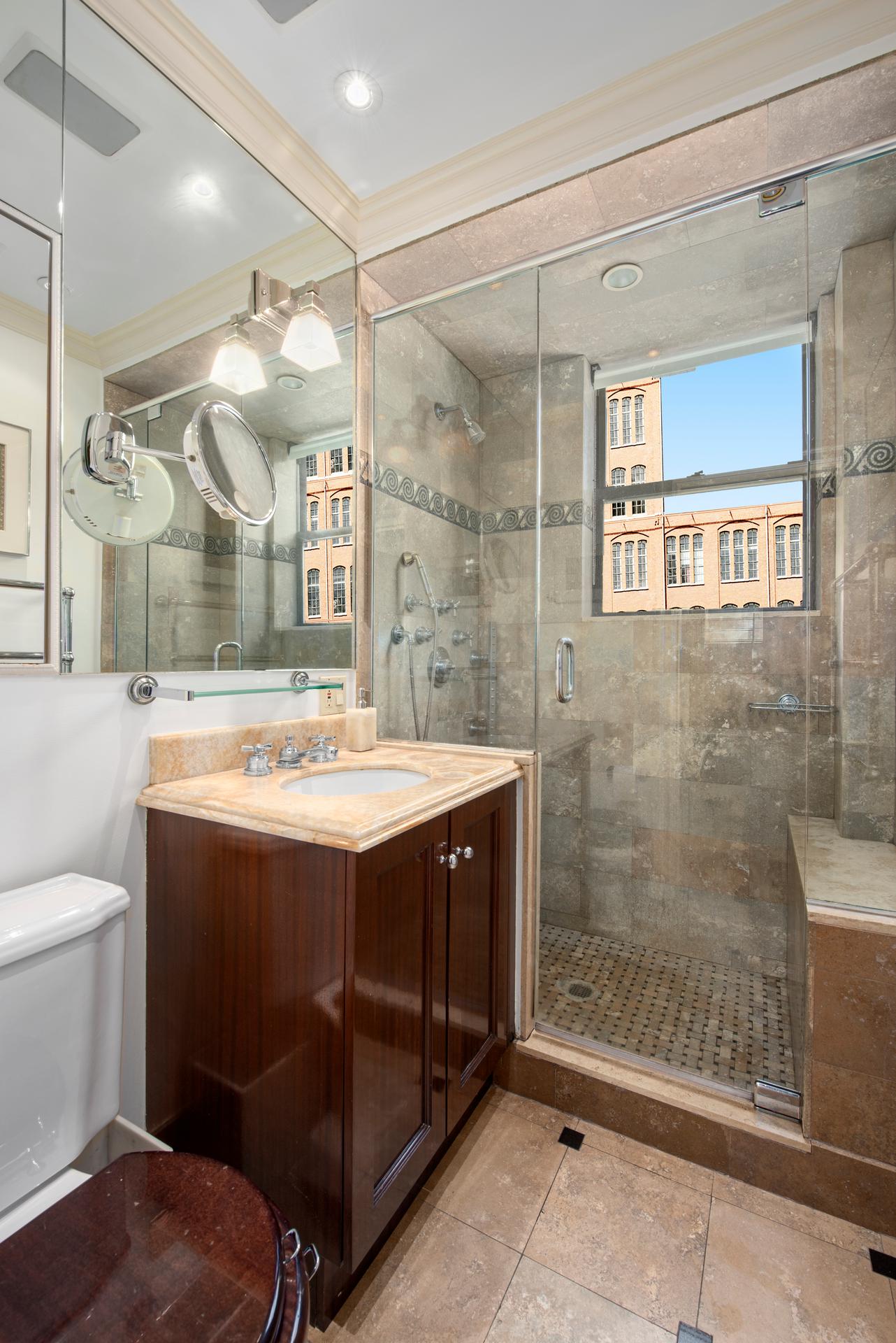 1140 5th Avenue, Unit 8C Manhattan, NY 10128 - Photo 11 of 16 a bathroom with a sink mirror and a shower