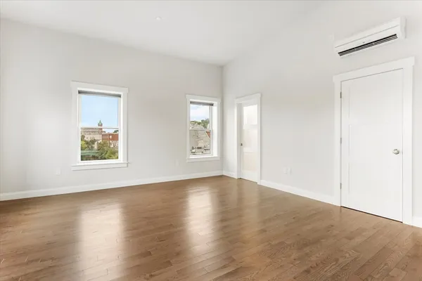 an empty room with wooden floor and windows