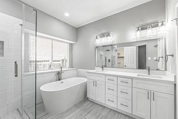 a spacious bathroom with a double vanity sink a mirror a bathtub and next to a window