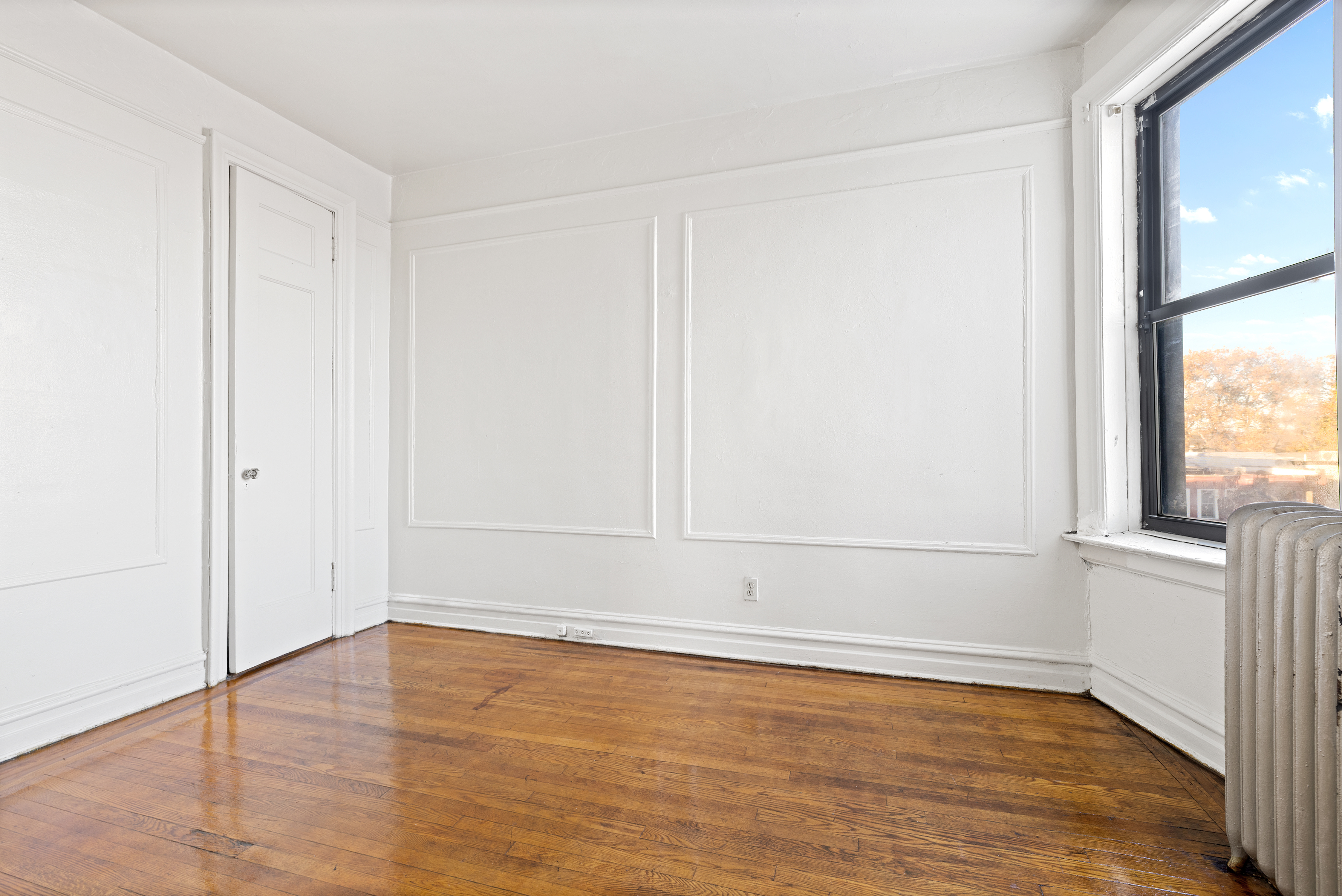 421 Crown Street, Unit 18R Brooklyn, NY 11225 - Photo 4 of 8 an empty room with wooden floor and windows