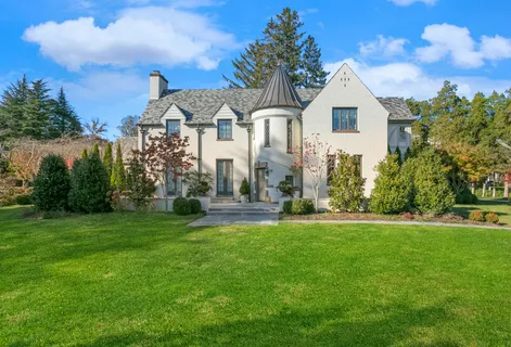 a view of a white house with a big yard and potted plants