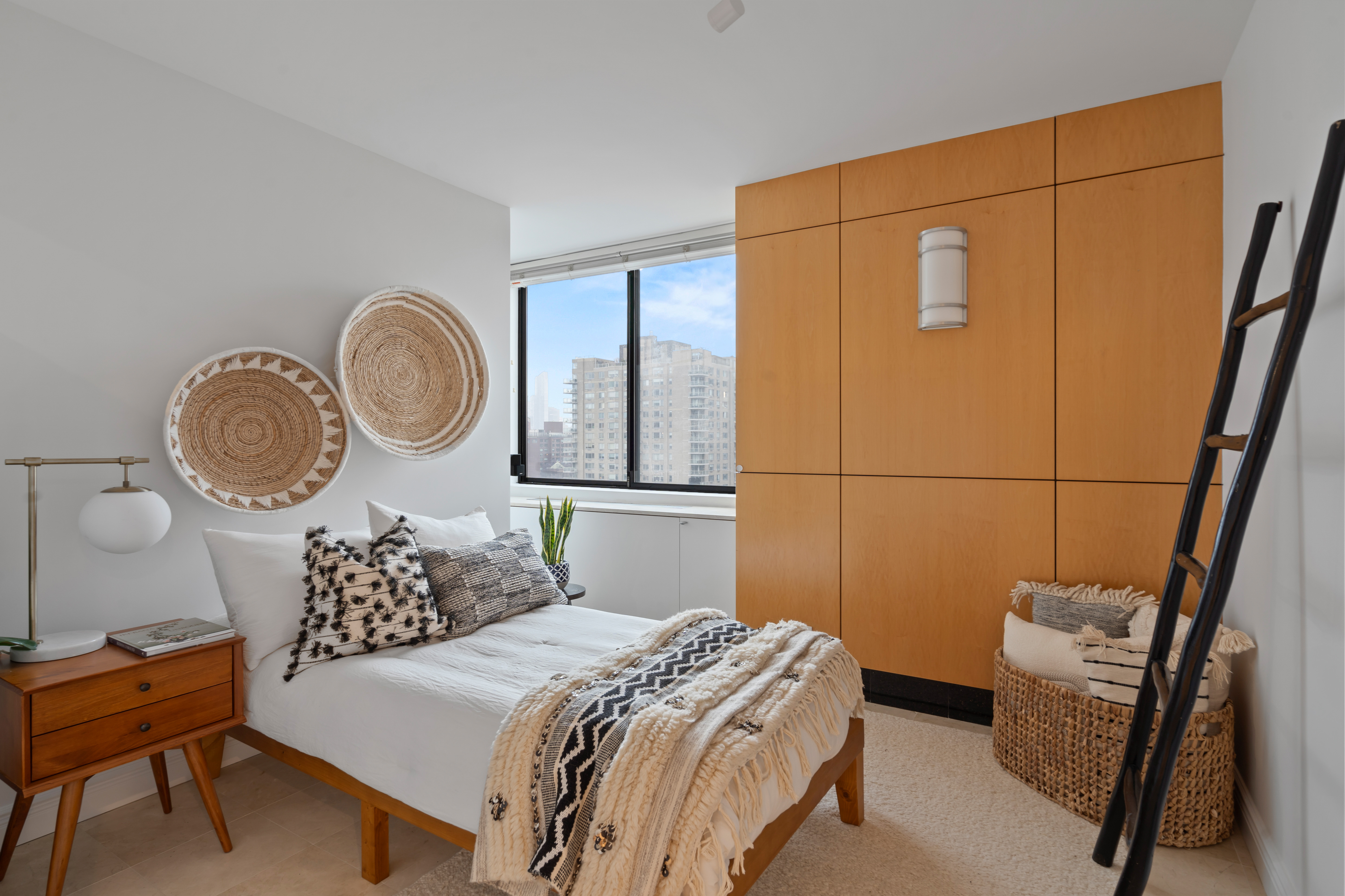 330 East 75th Street, Unit 32A Manhattan, NY 10021 - Photo 12 of 17 a bedroom with a bed a clock on wall and a large mirror next to a window