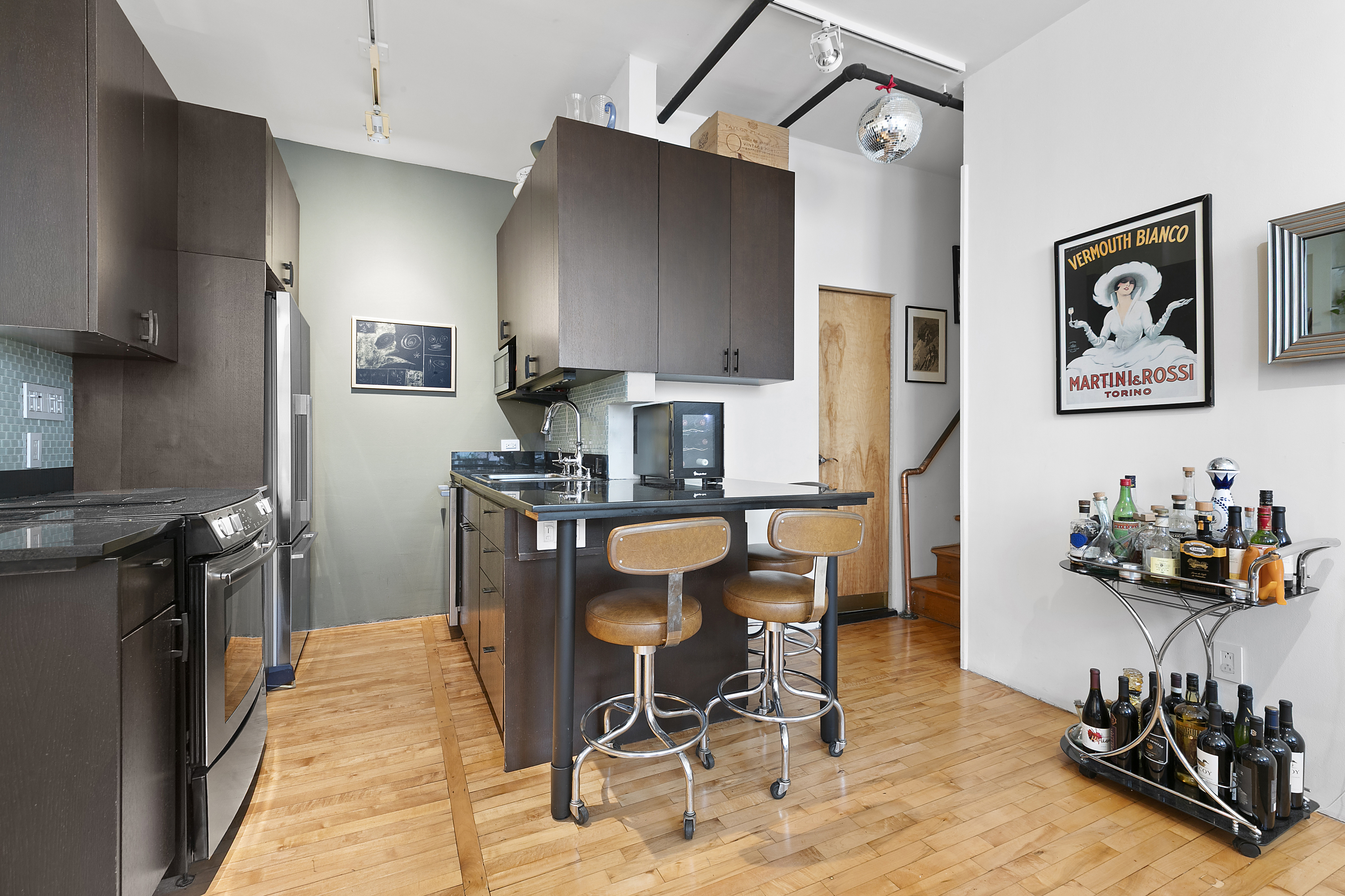 108 Wooster Street, Unit 4C Manhattan, NY 10012 - Photo 4 of 9 a kitchen with stainless steel appliances kitchen island granite countertop a refrigerator and a stove top oven