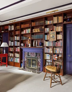 a living room with bookshelf a table and a fireplace