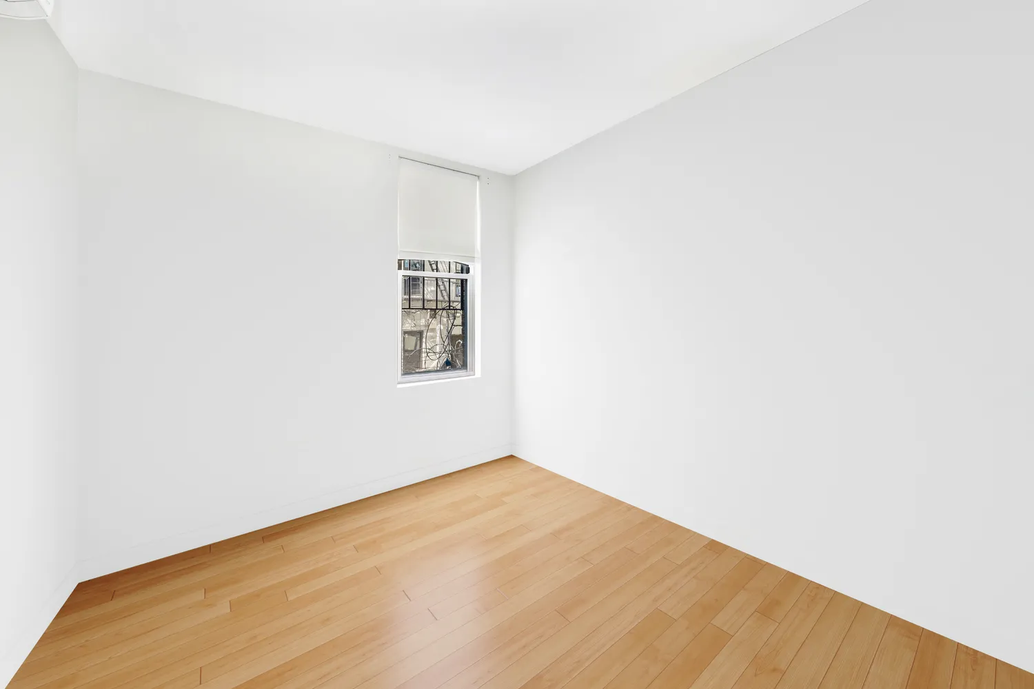 a view of a big room with wooden floor and a window