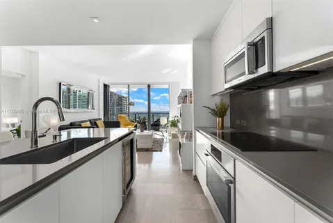 a large kitchen with stainless steel appliances a sink and a large window