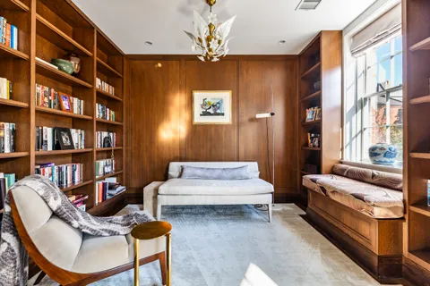 a living room with furniture a bookshelf and a window