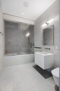 a bathroom with a bathtub shower sink mirror and toilet