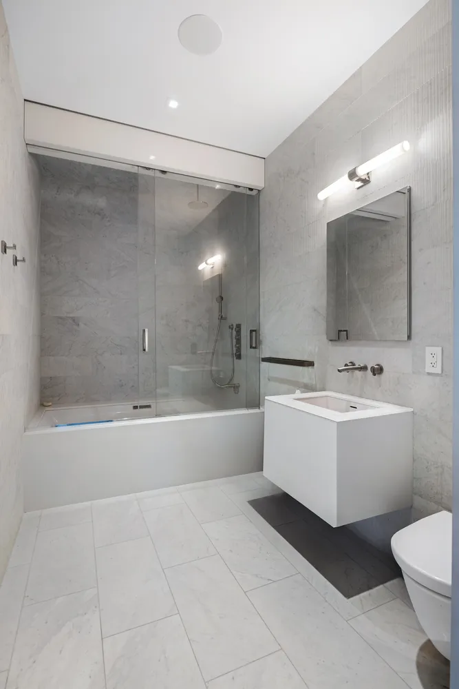a bathroom with a bathtub shower sink mirror and toilet