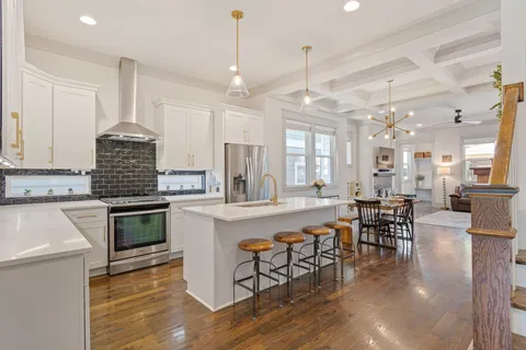 a kitchen with stainless steel appliances granite countertop a stove top oven a sink dishwasher a dining table and chairs with wooden floor