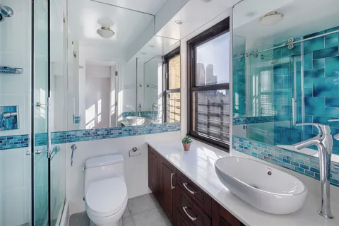 a bathroom with a granite countertop sink a toilet a mirror and shower