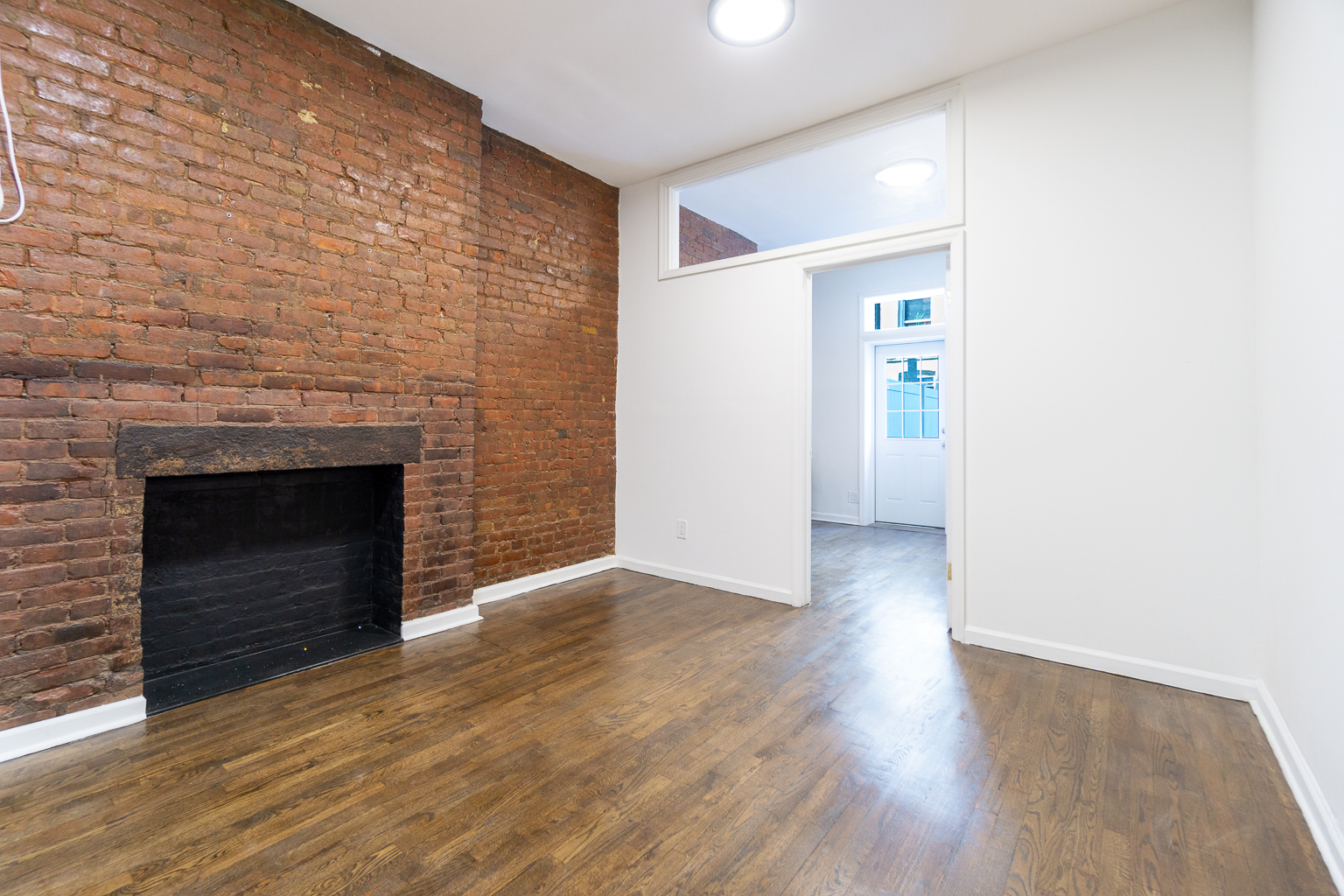 339 East 6th Street, Unit B Manhattan, NY 10003 - Photo 10 of 22 a view of an empty room with wooden floor and a fireplace