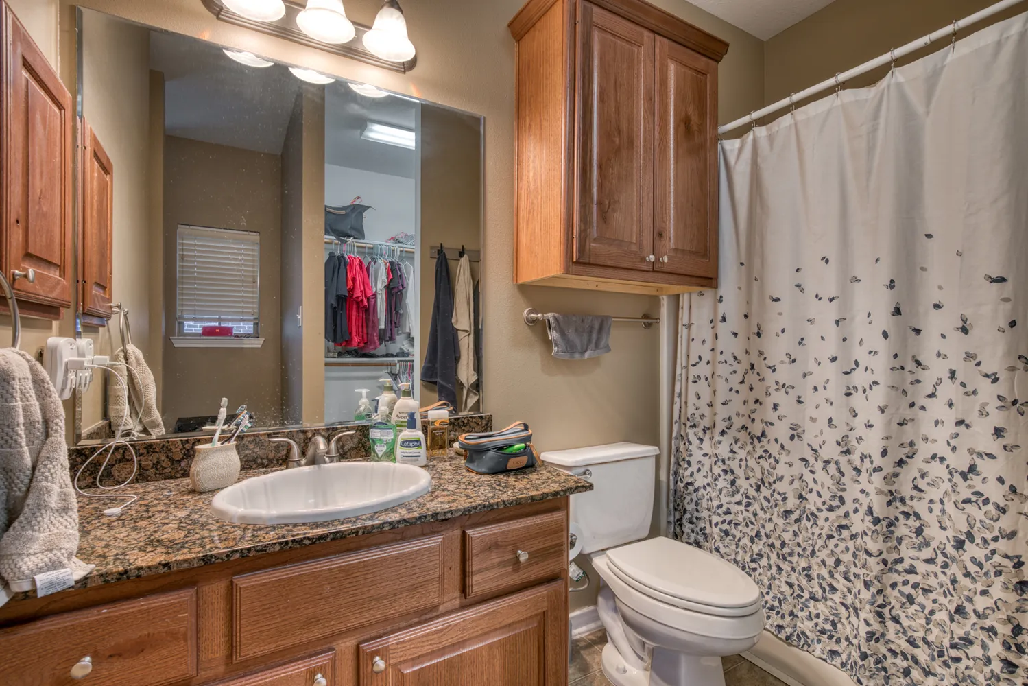 a bathroom with a granite countertop sink toilet and mirror
