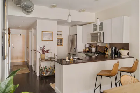 a room with stainless steel appliances kitchen island granite countertop furniture and a refrigerator