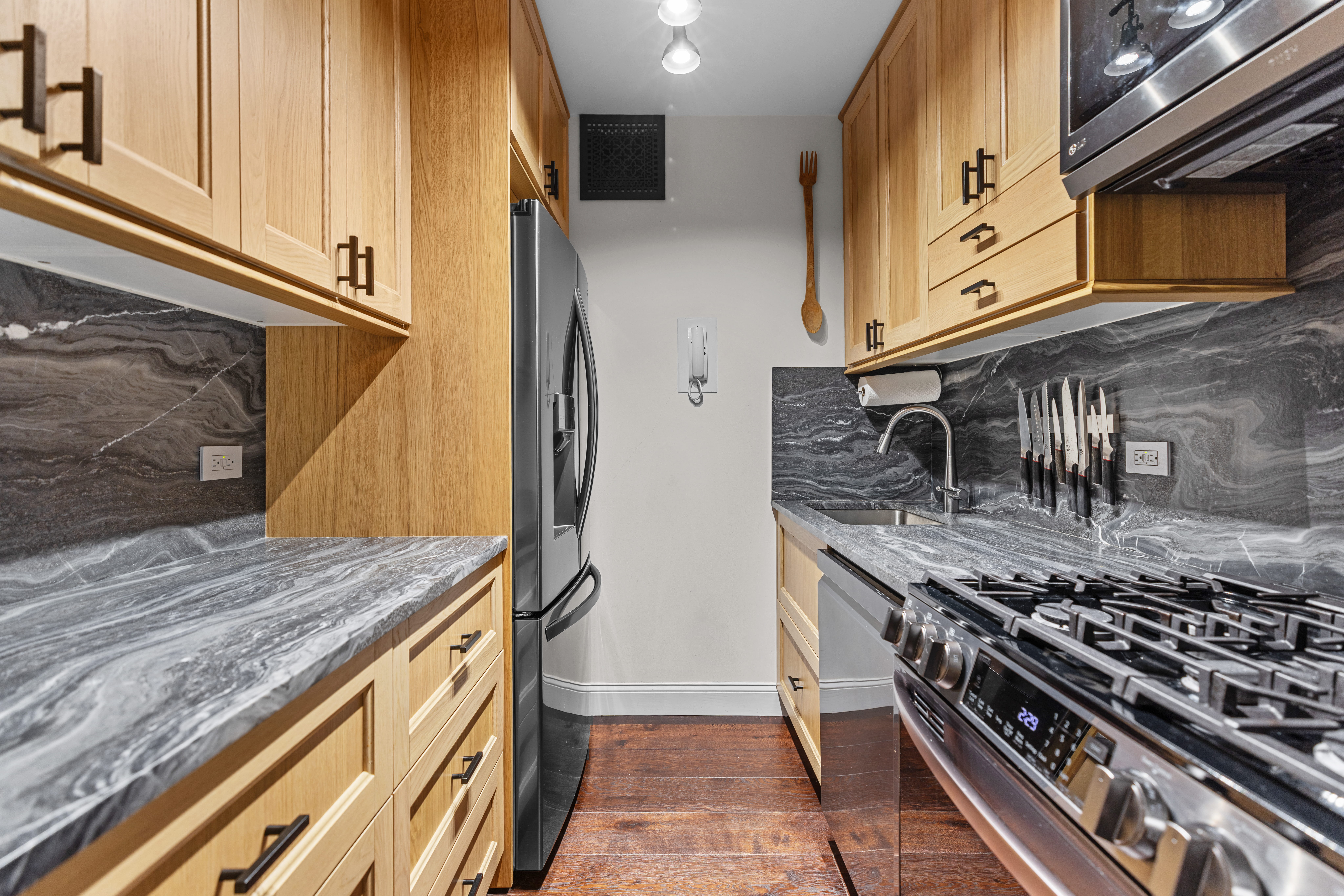 159 West 53rd Street, Unit 31F Manhattan, NY 10019 - Photo 5 of 16 a kitchen with stainless steel appliances granite countertop a stove and a microwave