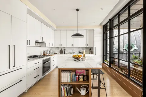 a kitchen with stainless steel appliances granite countertop a stove a refrigerator a sink dishwasher and white cabinets next to a window