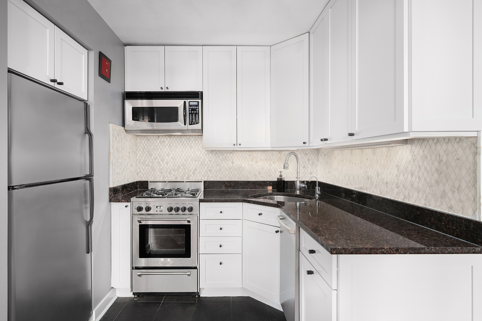 337 West 20th Street, Unit 1B Manhattan, NY 10011 - Photo 6 of 11 a kitchen with granite countertop white cabinets and stainless steel appliances