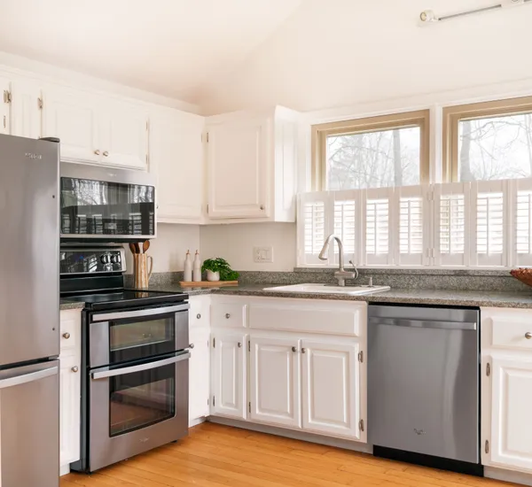a kitchen with granite countertop white cabinets and stainless steel appliances