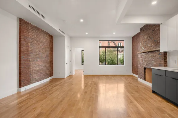 a view of an empty room with a window and wooden floor