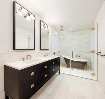 a bathroom with a double vanity sink mirror and bathtub