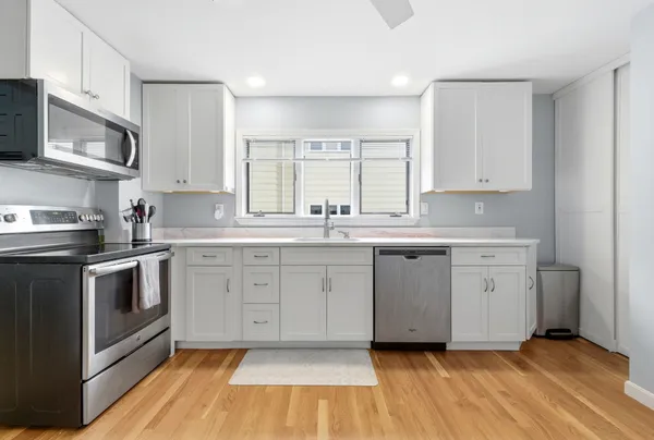 a kitchen with granite countertop a sink cabinets stainless steel appliances and a window