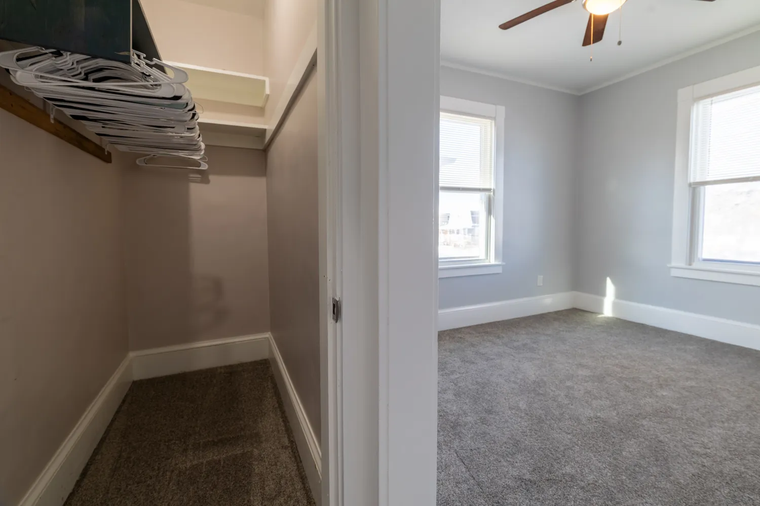 an empty room with chandelier fan and windows