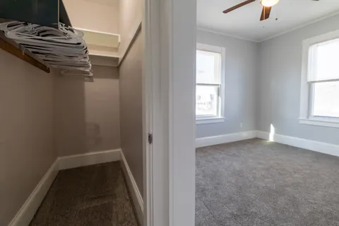 an empty room with chandelier fan and windows
