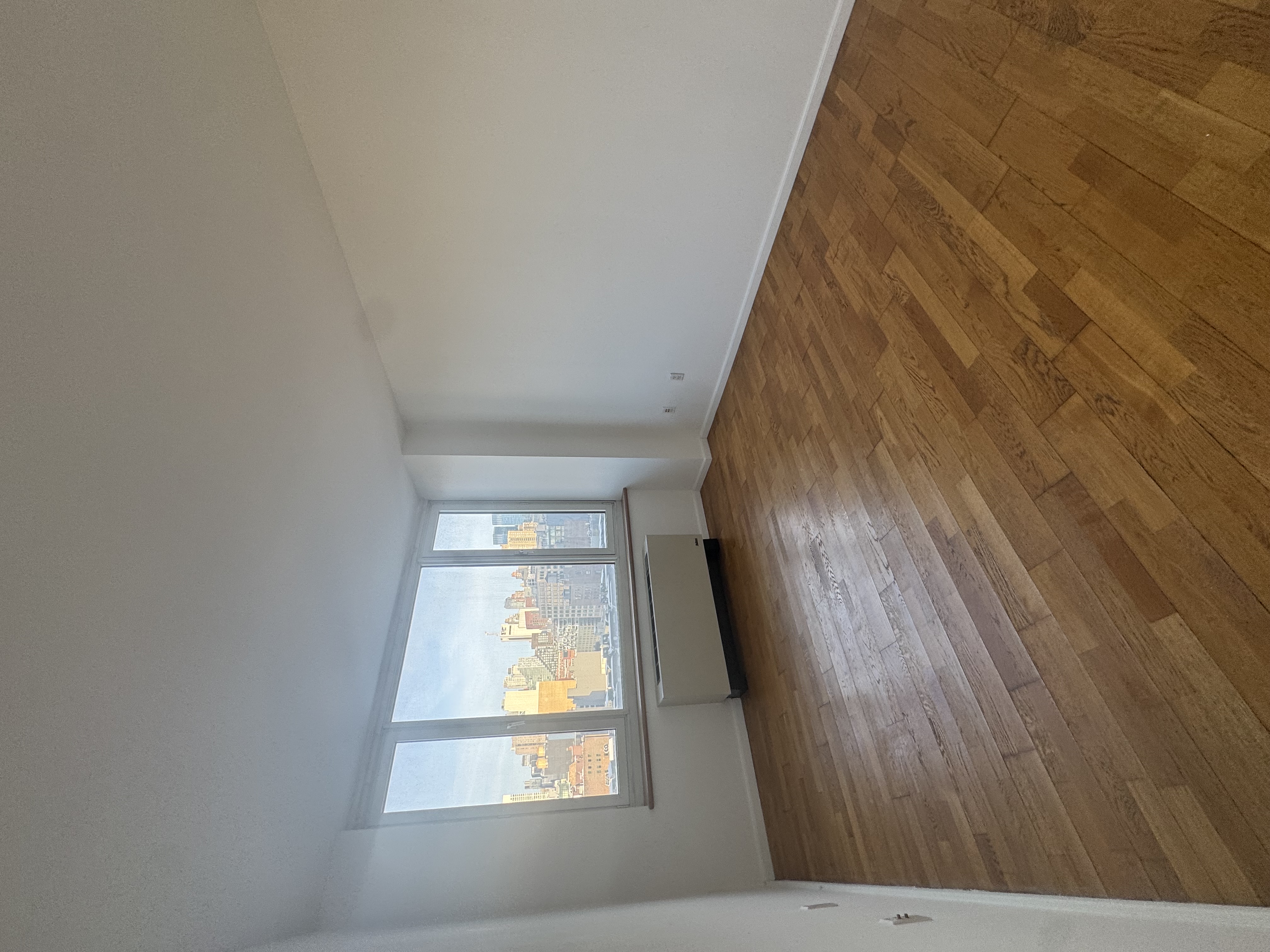 635 West 42nd Street, Unit 10C Manhattan, NY 10036 - Photo 4 of 10 an empty room with wooden floor and windows