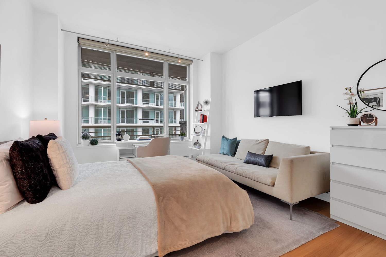 205 East 59th Street, Unit 19A Manhattan, NY 10022 - Photo 8 of 14 a bedroom with a bed a couch and a flat screen tv