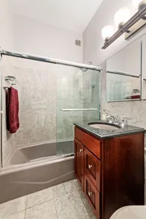 a bathroom with a granite countertop sink a mirror a bathtub and shower