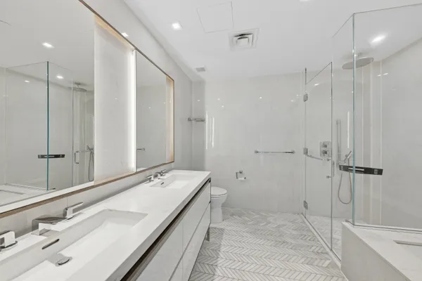 a bathroom with a double vanity sink and mirror with shower