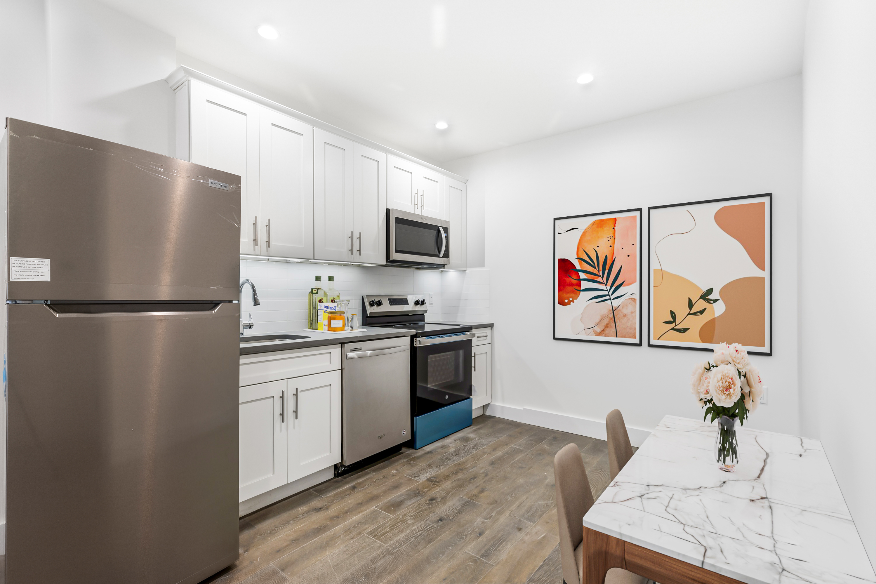 346 West 52nd Street, Unit 4D Manhattan, NY 10019 - Photo 3 of 7 a kitchen with stainless steel appliances granite countertop a refrigerator a stove a sink and a microwave
