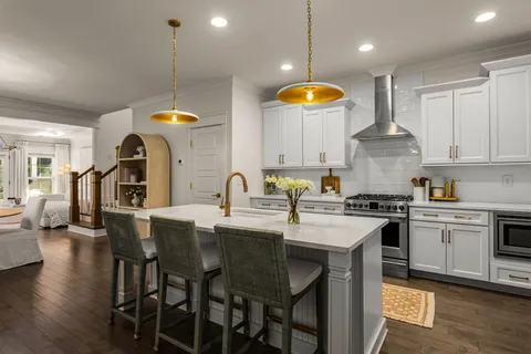 a kitchen with stainless steel appliances granite countertop a stove a sink a oven a dining table with chairs and wooden floor