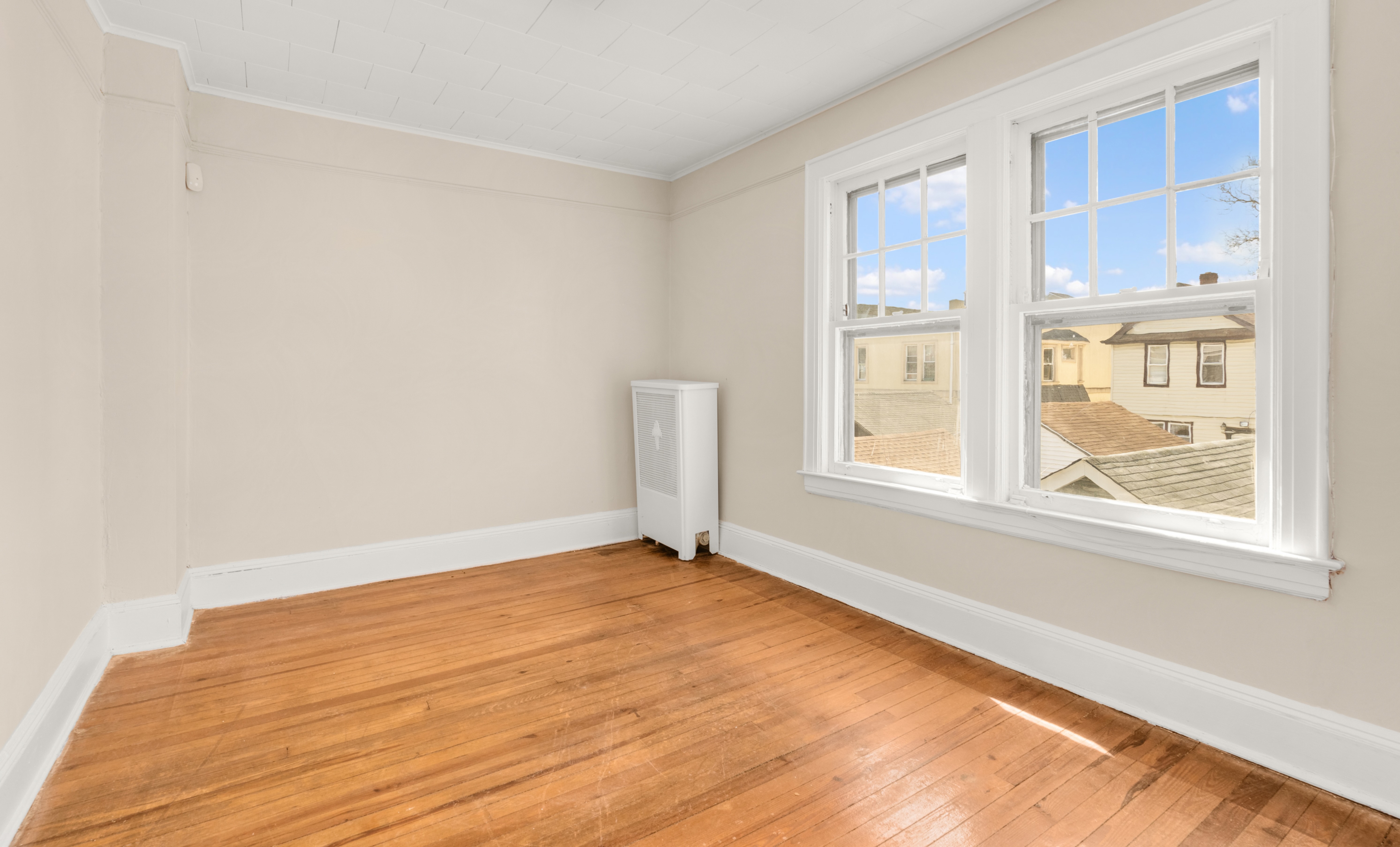 107-28 118th Street Queens, NY 11419 - Photo 6 of 12 an empty room with wooden floor and windows