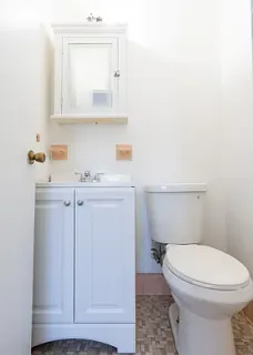 a bathroom with a toilet a sink and cabinet