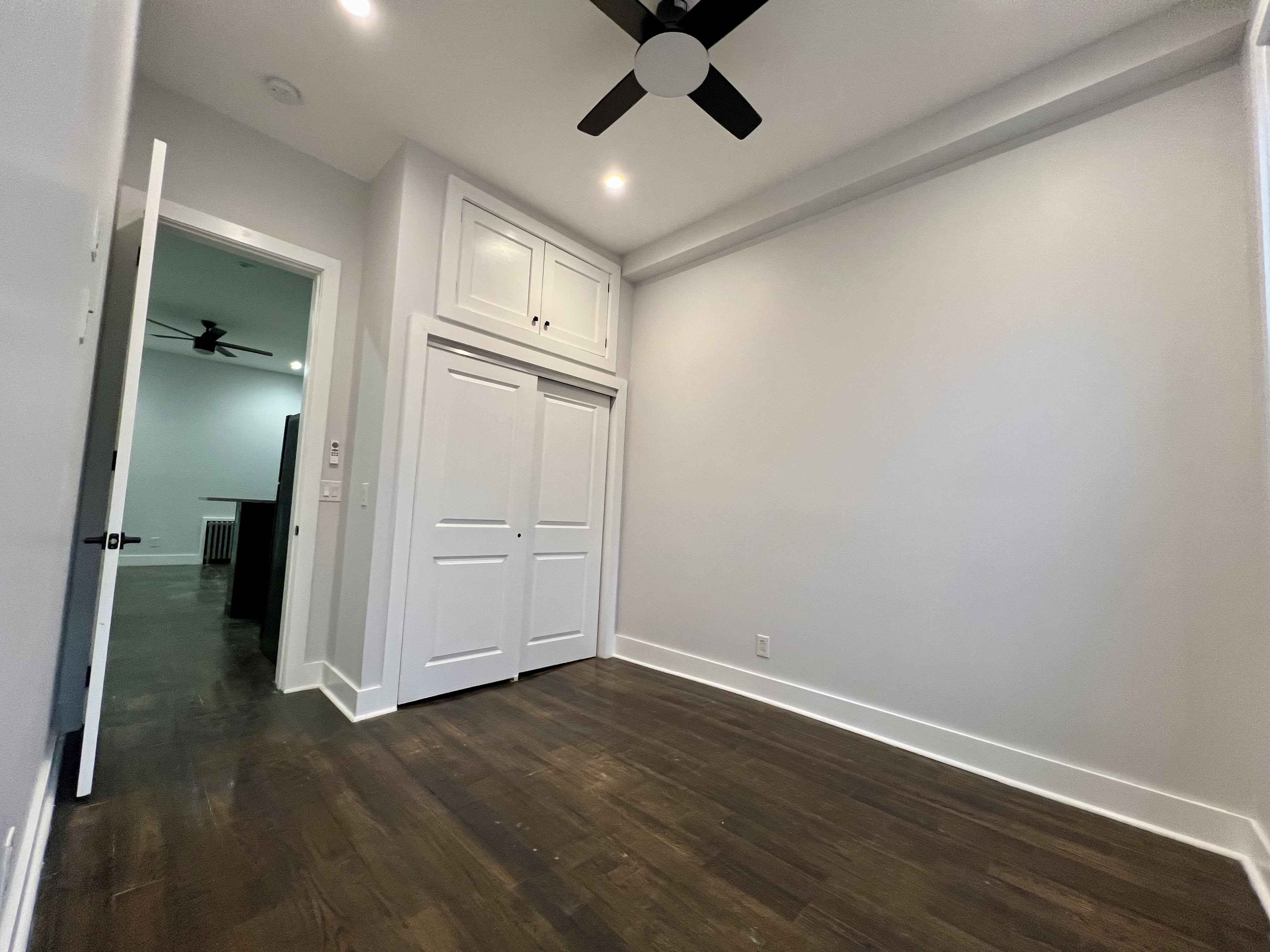 20 Suydam Street, Unit 1 Brooklyn, NY 11221 - Photo 5 of 10 an empty room with wooden floor and ceiling fan