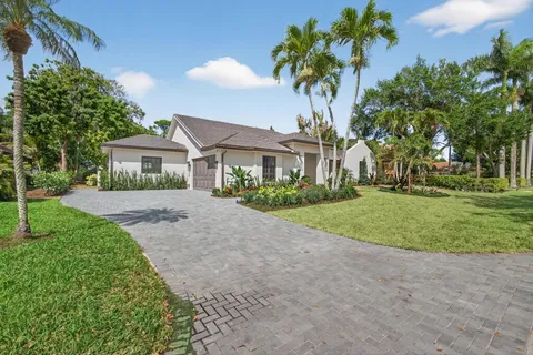 a front view of a house with a yard and palm trees