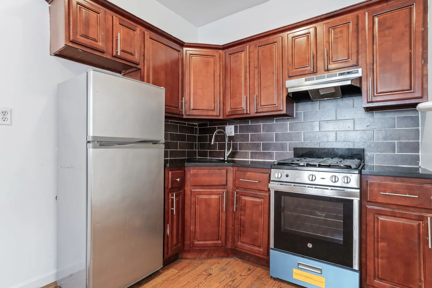 a kitchen with granite countertop a refrigerator stove and cabinets