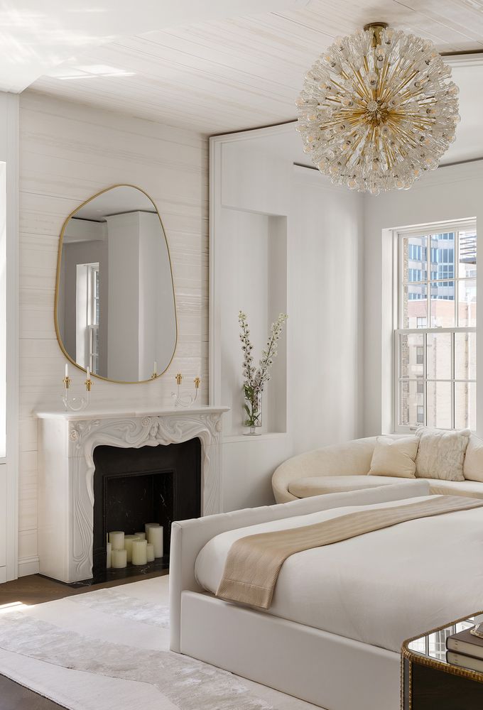 a bedroom with a bed a fireplace and a chandelier