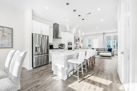 a kitchen with stainless steel appliances kitchen island granite countertop a refrigerator a stove a dining table and chairs